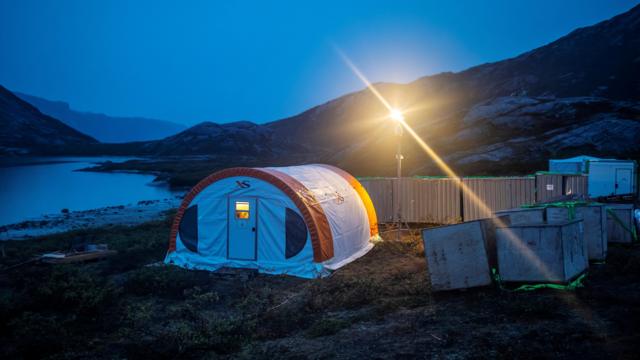 格陵兰矿业公司勘探基地营地,一顶帐篷在暮色中被一盏明亮的灯光照亮。
